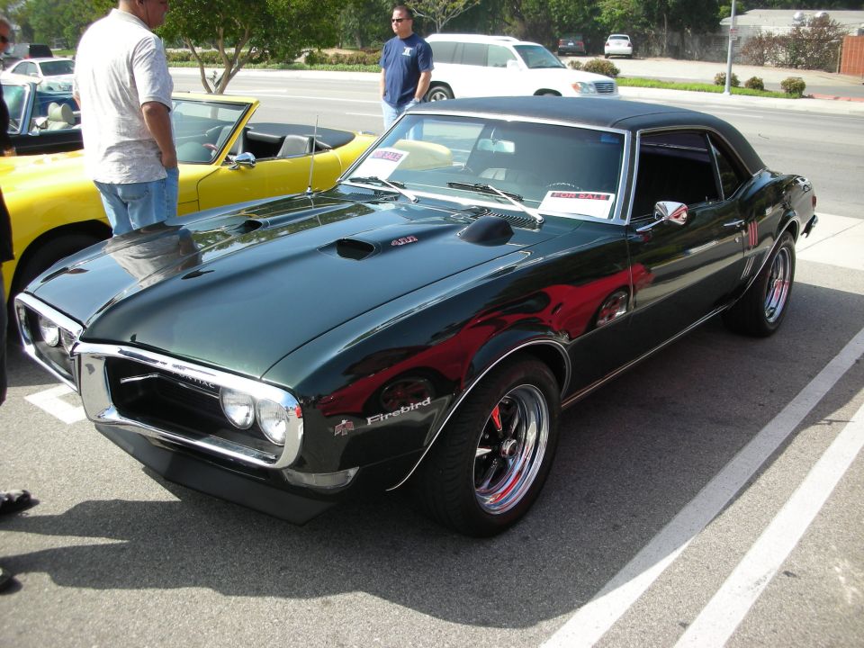 Dark green Pontiac Firebird with hood scoops and black wheels