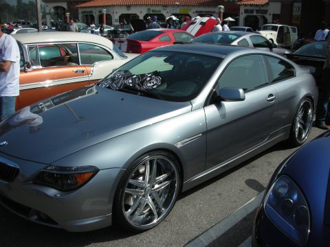 1998 Ford Crown Victoria - silver BMW 6 Series coupe parked at a car show with chrome multi-spoke wheels, surrounded by other cars and spectators.