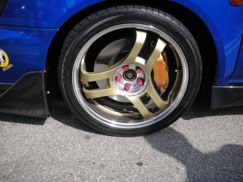 1998 Ford Crown Victoria - Detail of a gold Advan Racing four-spoke wheel and a yellow Brembo brake caliper on a blue car.