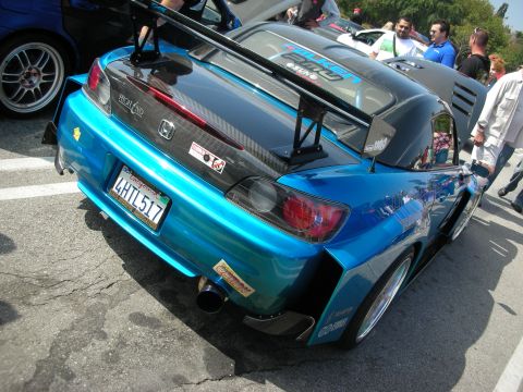 1998 Ford Crown Victoria - Rear quarter of a teal widebody Honda S2000 with a large carbon wing, parked among spectators at a car show.