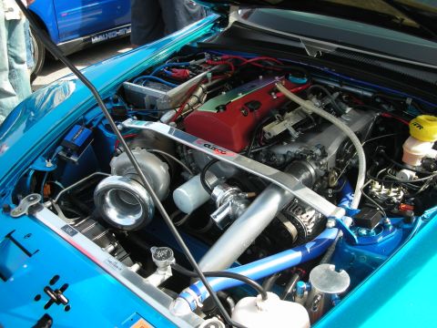 1998 Ford Crown Victoria - Close-up of a turbocharged engine with a red Honda valve cover, polished turbo and Cusco brace in a teal car.