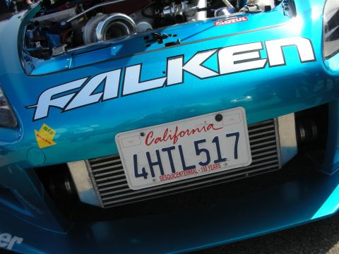 1998 Ford Crown Victoria - Close-up of a teal car's front bumper showing a large FALKEN decal, California plate 4HTL517 and a front-mount intercooler.