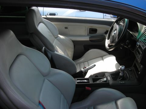 1998 Ford Crown Victoria - Gray leather interior of a two-seat coupe with manual shifter, center console and an M-tricolor stripe on the seat back.