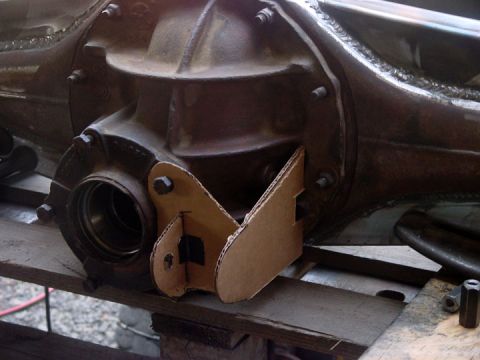 1979 Ford Bronco - A close-up view of a differential housing with a cardboard template for traction bar mounts, suggesting custom fabrication or modification.