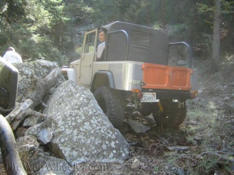 1987 Suzuki Samurai - A Toyota Land Cruiser FJ45 pickup navigates a rocky trail with a driver visible.