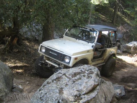 1987 Suzuki Samurai - A white Suzuki Samurai navigates a challenging, rocky off-road path.