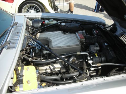 1998 Ford Crown Victoria - Open engine bay of a silver car showing a swapped V8 with a finned aluminum intake plenum and routed wiring and hoses.