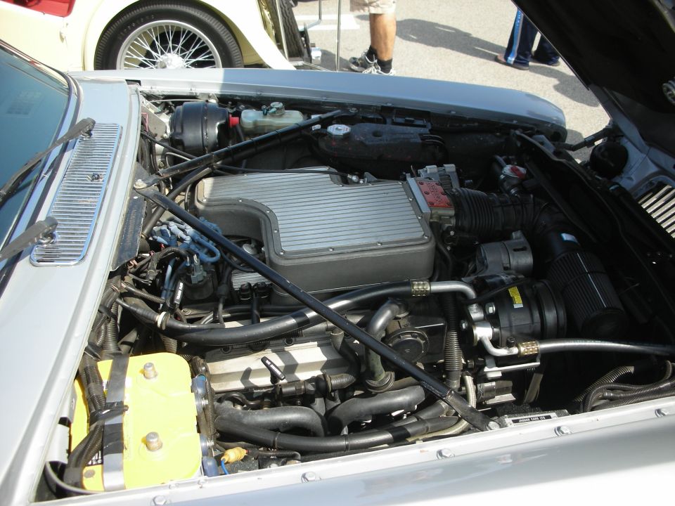 Engine bay of a silver car showing a V8 with finned intake plenum