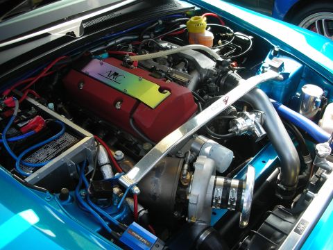 1998 Ford Crown Victoria - Turbocharged engine bay in a teal car featuring a red AKC valve cover, polished strut tower brace and large turbo piping.