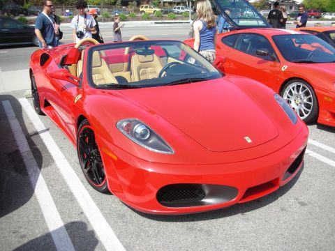 1998 Ford Crown Victoria - red Ferrari F430 Spider convertible with tan leather interior and black wheels, parked beside another red Ferrari.