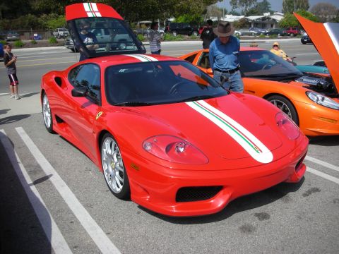 1998 Ford Crown Victoria - red Ferrari 360-style coupe with an Italian-flag racing stripe down the hood, parked among other show cars.