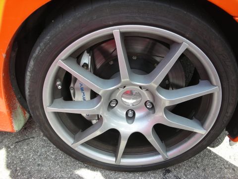 1998 Ford Crown Victoria - Close-up of a gray multi-spoke alloy wheel with low-profile tire and blue brake caliper on an orange sports car.