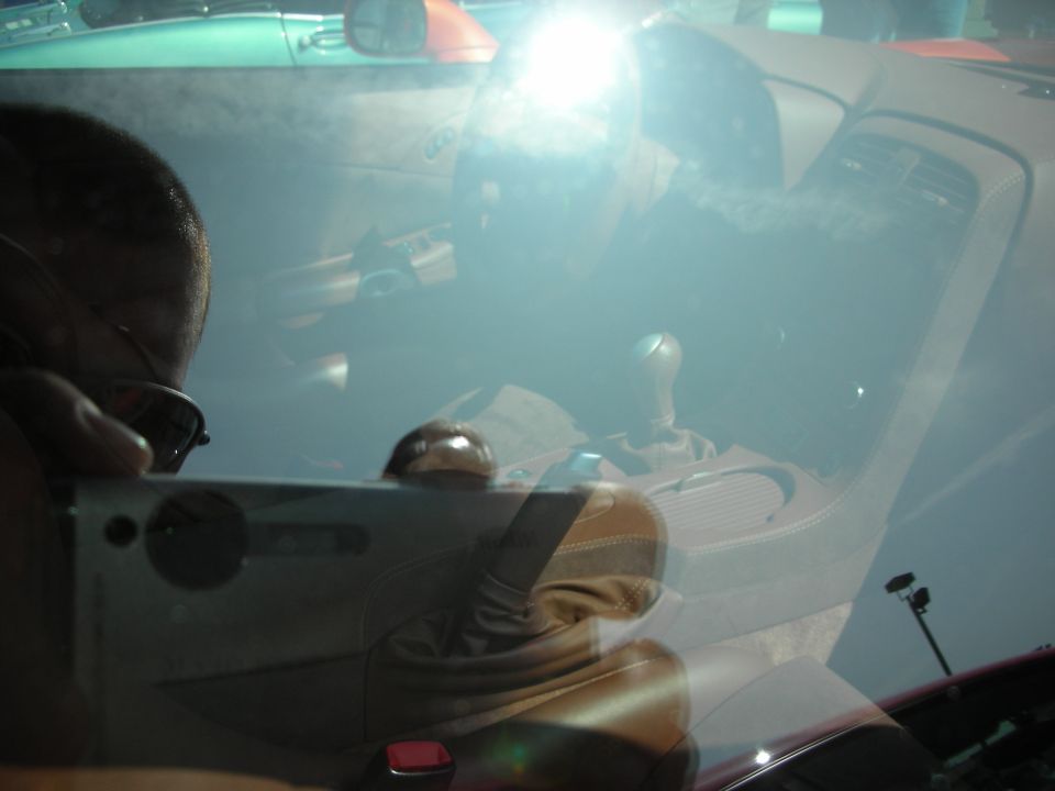 Reflective windshield view of a sports car interior with manual shifter