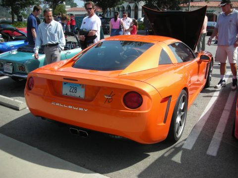 1998 Ford Crown Victoria - Rear three-quarter view of an orange Callaway sports car with raised rear hatch and round taillights at an outdoor car show.