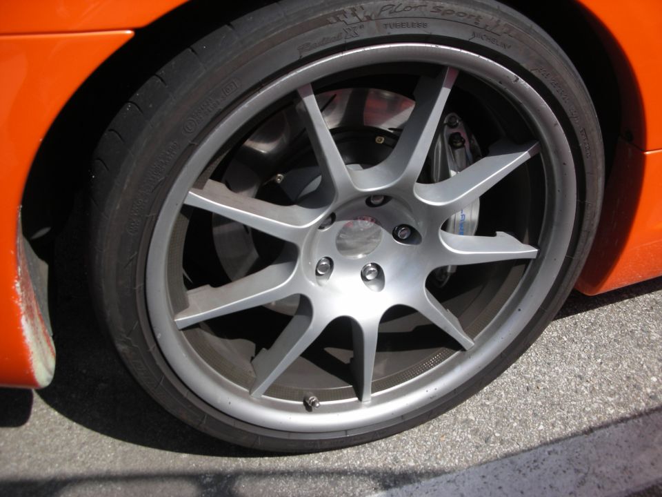 Gray ten-spoke alloy wheel with low-profile tire on orange car
