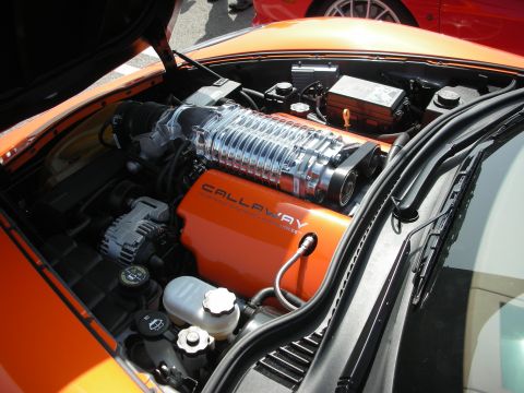 1998 Ford Crown Victoria - Engine bay of an orange sports car showing a polished supercharger and an orange Callaway-branded engine cover.
