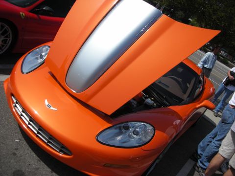 1998 Ford Crown Victoria - Front end of an orange Callaway sports car with its hood raised, a silver center stripe and a red Ferrari nearby.