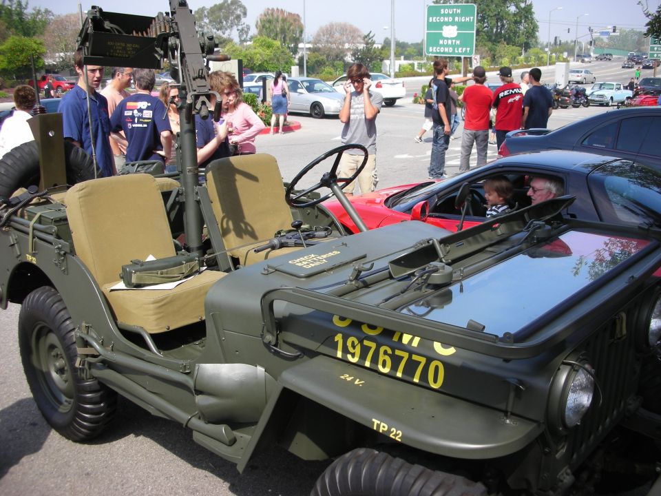 Military Jeep marked USMC 1976770 beside red sports car