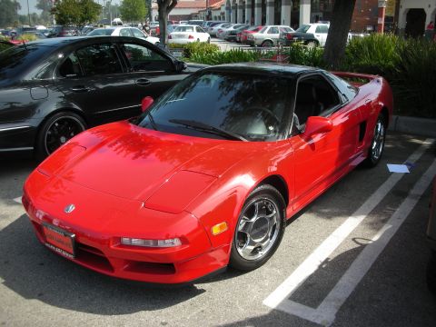 1998 Ford Crown Victoria - Front three-quarter view of a red Acura NSX sports car parked in a lot with other vehicles in the background.