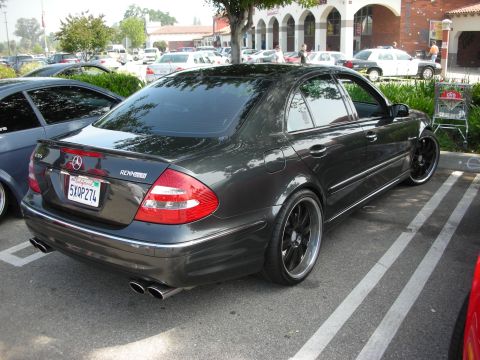 1998 Ford Crown Victoria - Rear three-quarter view of a dark gray Mercedes-Benz E-class sedan lowered on black multi-spoke wheels in a parking lot.