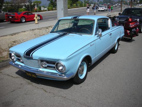 1998 Ford Crown Victoria - Front three-quarter view of a light blue 1960s Plymouth fastback with black hood stripes parked roadside near a red Ferrari.