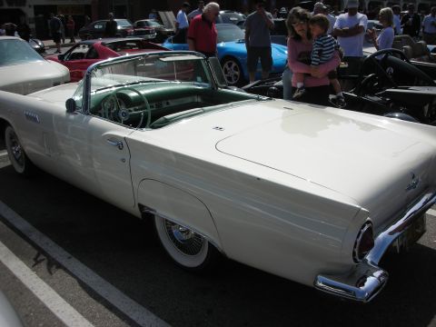 1998 Ford Crown Victoria - Rear three-quarter view of a white classic Ford Thunderbird convertible with wire wheels and green interior at a car show.