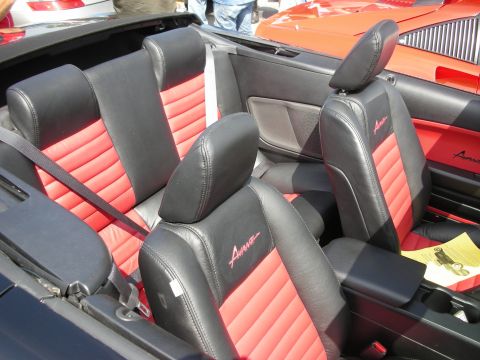 1998 Ford Crown Victoria - Close view of black-and-red leather convertible seats with 'Avanti' script embroidery, seen over the seatbacks of an open-top car.
