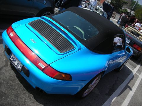 1998 Ford Crown Victoria - light-blue Porsche 911 convertible seen from the rear, soft top up, wearing a vanity plate reading 'MWM BLU' at a car show.