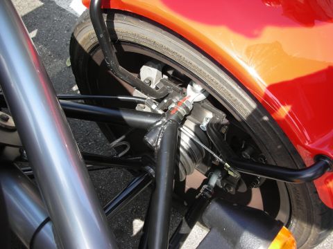 1998 Ford Crown Victoria - Detail of an exposed rear wheel showing coil-over suspension, brake caliper and tubular framing beneath red bodywork.