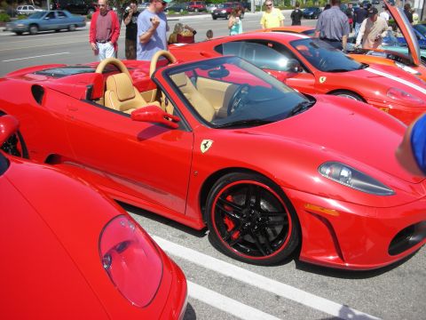 1998 Ford Crown Victoria - red Ferrari F430 Spider with tan interior and black red-pinstripe wheels parked among other red Ferraris at a car show.