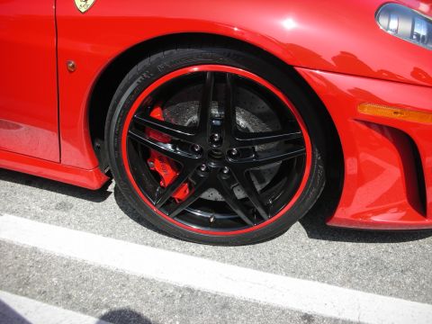 1998 Ford Crown Victoria - Close-up of a red Ferrari's black five-spoke wheel with a red rim pinstripe, red brake caliper and the prancing-horse fender shield.