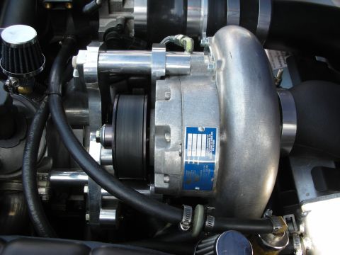 1998 Ford Crown Victoria - Tight close-up of a polished belt-driven supercharger with a blue manufacturer ID label and small cone air filters in an engine bay.