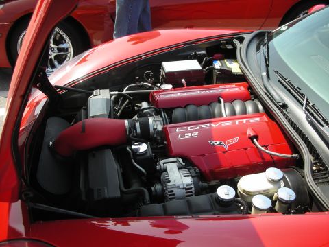1998 Ford Crown Victoria - red-painted Corvette LS2 V8 engine bay with a red intake tube and chrome accents under an open hood.