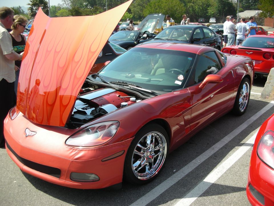Copper Chevrolet Corvette coupe with flame-painted open hood at car show