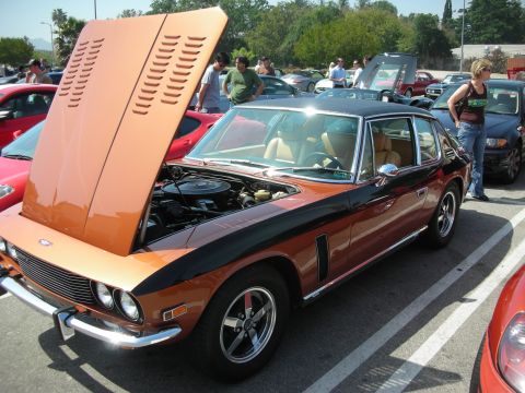 1998 Ford Crown Victoria - copper-and-black Jensen Interceptor grand tourer with its hood raised, parked among cars with onlookers nearby.