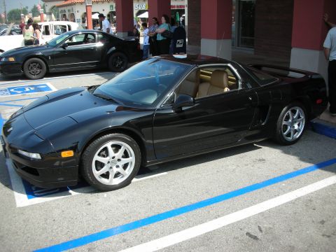 1998 Ford Crown Victoria - black Acura NSX targa sports car with a tan interior parked in a striped lot near a strip mall.