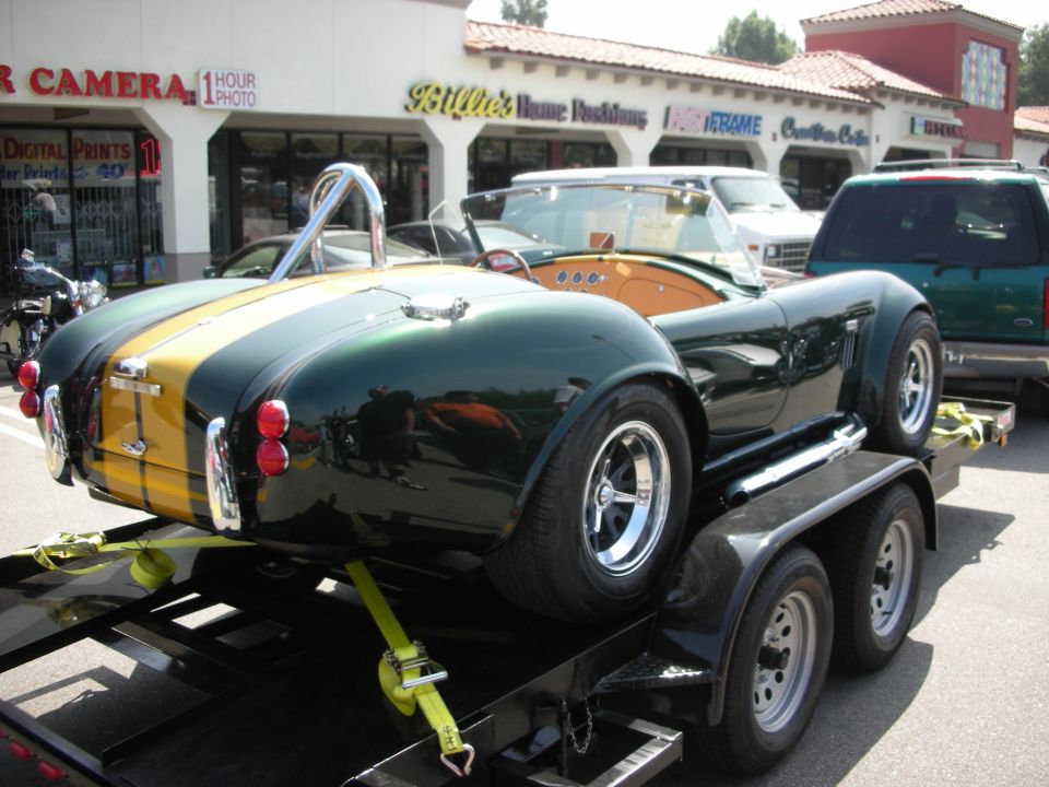 Rear of green and gold Cobra roadster loaded on car trailer
