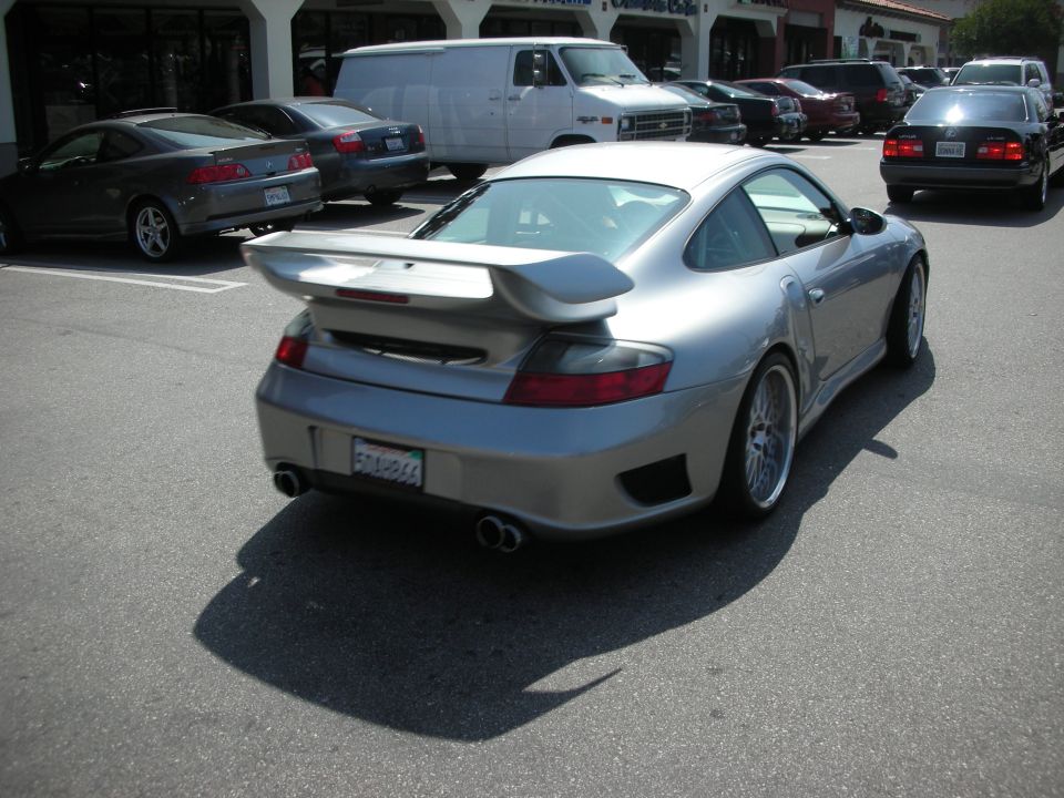 Rear of silver Porsche 911 coupe with raised wing in parking lot