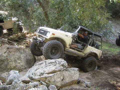 1987 Suzuki Samurai - A Suzuki Samurai tackles a challenging rocky terrain, with another vehicle in the background.