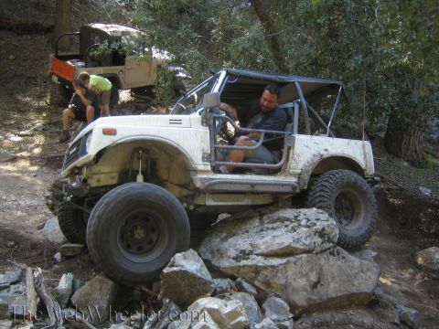 1987 Suzuki Samurai - A white 1987 Suzuki Samurai navigates a rocky trail with another vehicle in the background.