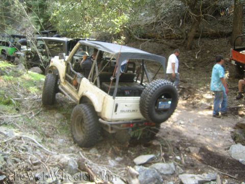 1987 Suzuki Samurai - Several Suzuki Samurai vehicles navigate a wooded, rocky off-road trail.
