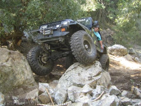 1987 Suzuki Samurai - Jeep Wrangler TJ navigating a difficult rocky trail with a driver visible.