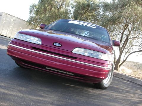 1992 Ford Crown Victoria - A maroon 1992 Ford Crown Victoria is parked outdoors with a banner across the top of the windshield.