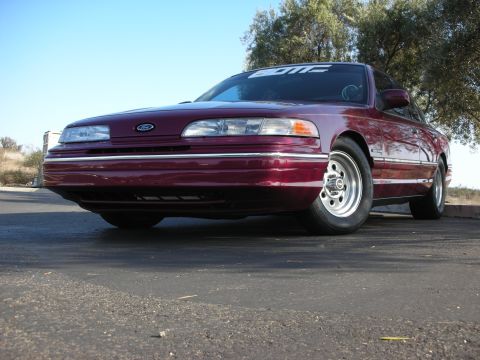 1992 Ford Crown Victoria - A maroon 1992 Ford Crown Victoria is shown with a lowered stance and custom wheels, possibly indicating aftermarket suspension modification…