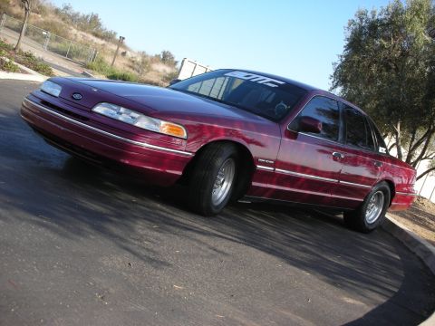 1992 Ford Crown Victoria - A maroon 1992 Ford Crown Victoria is parked on an asphalt surface under a clear blue sky.