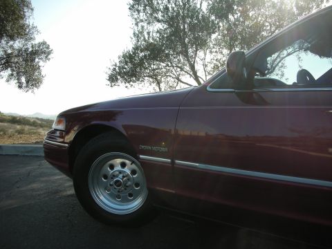 1992 Ford Crown Victoria - A maroon 1992 Ford Crown Victoria is shown from the front quarter, highlighting its lowered profile.