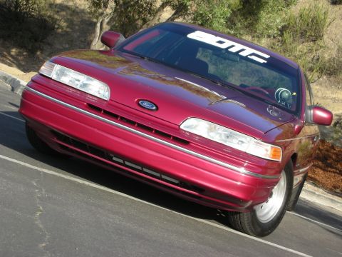 1992 Ford Crown Victoria - This 1992 Ford Crown Victoria features a front 3/4 view, its lowered stance and a 'DOMC' banner on the windshield.