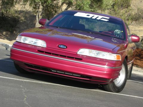 1992 Ford Crown Victoria - Front view of a red 1992 Ford Crown Victoria, showing the grille and headlights. A 'BOMC' sticker is visible on the windshield.
