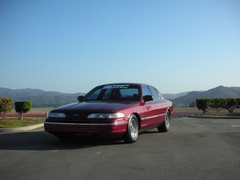 1992 Ford Crown Victoria - Maroon 1992 Ford Crown Victoria parked outdoors with a clear blue sky and distant hills in the background.