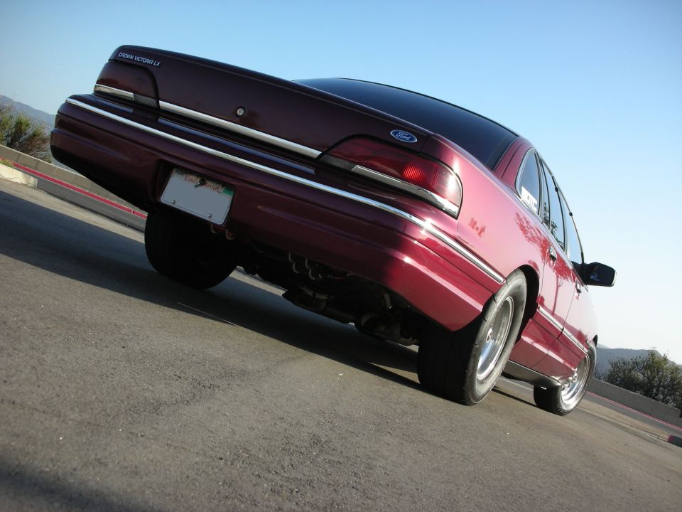 Low rear angle of maroon Ford Crown Victoria LX sedan with chrome trim and dual exhaust